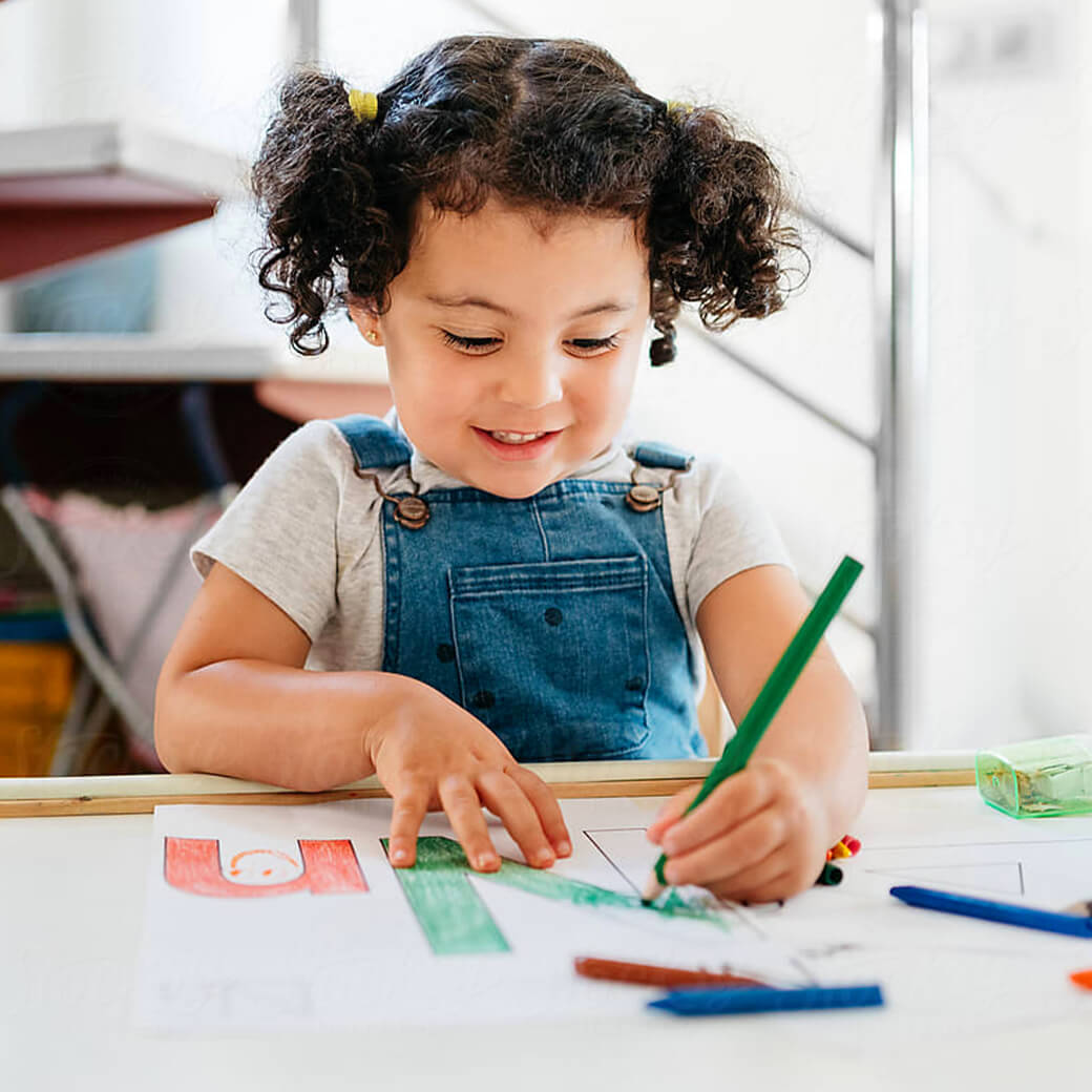 Little girl sitting at table coloring.