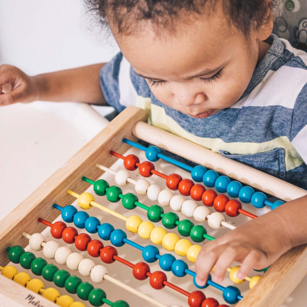 young child plays with abacus