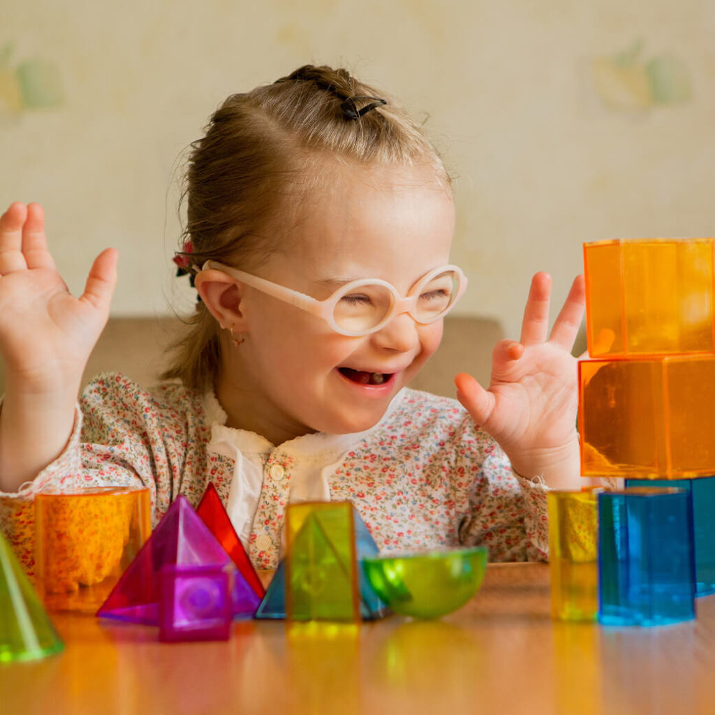 A little girl with down's syndrome lays out geometric shapes on table.